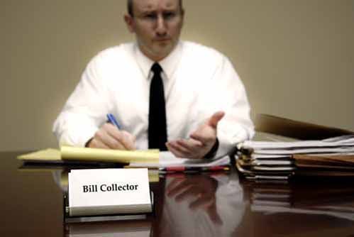 A man sits at a desk with business cards that say 'Bill Collector